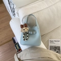 Detalle del bolso de cubo en cuero azul claro con textura de grano y colgante de osito - Azul con Colgante