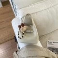 Detalle de bolso tipo cubo blanco crema en cuero granulado con un lindo colgante de oso - Beige Con Amuleto