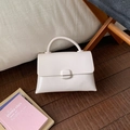 Dettaglio ravvicinato di una borsa quadrata bianca lucida con manico su pavimento in legno - Bianco