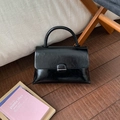 Detail of minimalist black leather square handbag with shiny texture and silver clasp - Black