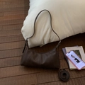 Detailed macro view of deep brown dumpling bag with high-quality lychee grain texture - Brown