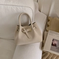 Chic beige bucket bag with gold buckle on a white sofa with decorative background - White Without Pendant