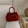 Detail shot of a dark red suede bucket bag with a belt buckle on a stylish sofa - Red (No Pendant)