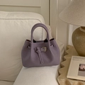 Detail of a purple bucket bag with gold clasp on a beige fabric sofa background - Purple Without Pendant