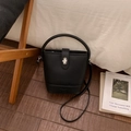 Detail of black lychee grain bucket bag with silver twist lock and adjustable strap - No Pendant / Black