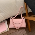 Detailed macro view of the light pink lychee texture leather and gold logo on the handbag - Pink