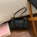 Detail of black lychee grain leather bag with unique trapezoid shape and matte chain - Black