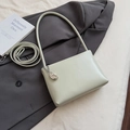 Detail of minimalist beige underarm bag with silver fashion charm on a grey blazer - Green with Charm