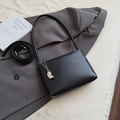 Detail view of black minimalist underarm bag with metal chain and bean pendant on blazer - Black With Pendant