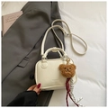 Close-up of cream white Boston bag with litchi grain texture and cute bear charm - White With Pendant
