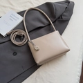 Close-up of a beige underarm bag with smooth faux leather and silver bean charm accessory - With Pendant Style / Khaki With Pendant