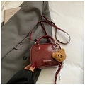 Detail of dark burgundy patent leather crossbody bag with teddy bear charm and fashion logo - Wine Red with Pendant
