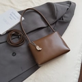 Detailed view of dark brown leather underarm bag with metal chain and bean-shaped pendant - With Pendant Style / Brown with Pendant