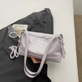Detailed close-up of soft purple leather shoulder bag with silver zipper and strap buckle - Purple