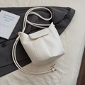 Sac seau blanc chic avec texture litchi et bandoulière tressée sur un costume gris - Blanc