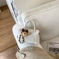Detailansicht der weißen Boston-Tasche mit Logo-Prägung, Plüschbär und Perlenketten - Weiß (Mit Anhänger)