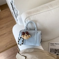 Nahaufnahme der hellblauen Boston-Tasche aus Leder mit Bärenanhänger auf Sofa - Blau Mit Anhänger
