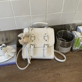 Close-up of white minimalist square crossbody bag with a cute plush dog charm accessory - Beige