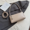 Detailed macro view of beige baguette bag with metallic charm and adjustable strap - Khaki With Pendant