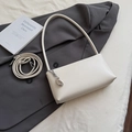 Detail of off-white faux leather baguette bag with silver fashion pendant on a blazer - White With Pendant