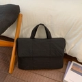 Detail of black quilted laptop bag showing padded stitching and durable handles - Black