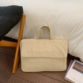 Detalle de funda acolchada beige para portátil con asa acolchada en suelo de madera - Blanco Roto
