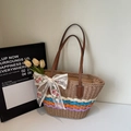 Close-up of handmade straw tote featuring colorful stripes and floral lace bow decoration - Khaki