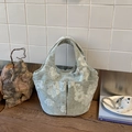 Dettaglio di borsa a mano in tessuto ricamato con motivi floreali e tasche frontali - Verde