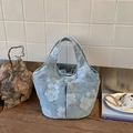 Dettaglio della borsa a secchiello in tela ricamata azzurra con tasche laterali - Blu
