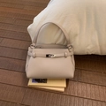 Close-up of minimalist pebble leather handbag featuring premium metal buckle and strap detail - Purple