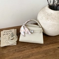 Gros plan d'un sac à main en cuir crème avec anse en foulard de soie sur table - Blanc Cassé