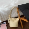 Détail d'un sac seau crème avec texture lychee, bandoulière nouée et mini pochette - Jaune