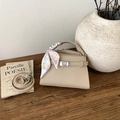 Détail d'un sac à main beige en cuir grainé avec fermoir argenté et foulard en soie - Abricot
