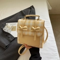 Detail of yellow and white plaid backpack with decorative bows in a lifestyle setting - Yellow