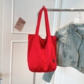 Detail of red large capacity tote bag with Yes Honey label hanging on metal rack - Red