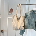 Detail view of beige canvas tote bag hanging on a rack with a casual outfit - Beige