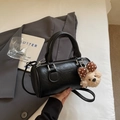 Close-up of black leather Boston bag with teddy charm and luxury embossed logo detail - Black (With Plush Charm)
