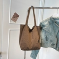 Detail of a brown nylon tote bag with wide strap hanging next to a denim jacket - Brown