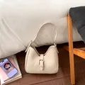 Detailed close-up of a semi-circular off-white leather underarm bag with silver buckle - Khaki