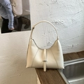 Detail of cream leather shoulder bag with vertical stitching and slim strap on wood - White