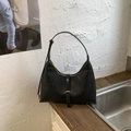 Detail of black leather crescent hobo bag with gold buckle on a wooden surface - Black
