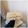 Close-up of cream leather shoulder bag with elegant gold metal buckle on top of books - Khaki