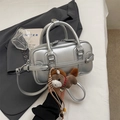 Silver bowling handbag with metallic finish and brown pony charm on a gray blazer - With Charm / Silver