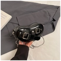 Detailansicht einer schwarzen herzförmigen Handtasche mit Silberschnallen auf grauem Blazer - Schwarz