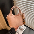 Detail of light pink leather bucket bag with metallic logo and beaded wooden charm - Pink