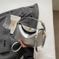 Silver leather shoulder bag with golden buckle on a white bed with aesthetic props - Silver