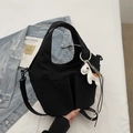 Close-up of black nylon tote with two front pockets and a white pony charm detail - Black (With Ornament)