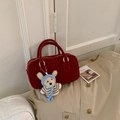 Détail du sac Boston rouge mat avec gaufrage carré et un charmant pendentif d'ours en peluche - Rouge avec pendentif