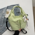 Detail of light green bucket bag with twin front pockets and a white pony charm - Green (With Pendant)