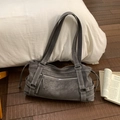 Detalle de bolso tote vintage gris oscuro con correas y cremallera plateada sobre madera - Gris